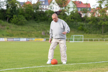 An elderly man goes in for sports on the background of the stadium on a summer evening
