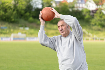 An elderly man goes in for sports on the background of the stadium on a summer evening