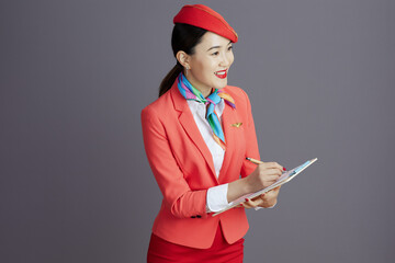 smiling stylish air hostess asian woman against grey background