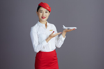 happy stylish asian female air hostess isolated on gray