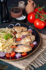 Front view of raw pastas chickens and vegetables on a plate on nude towel and cutlery set tomatoes spices wooden hammer on green black mix colors background