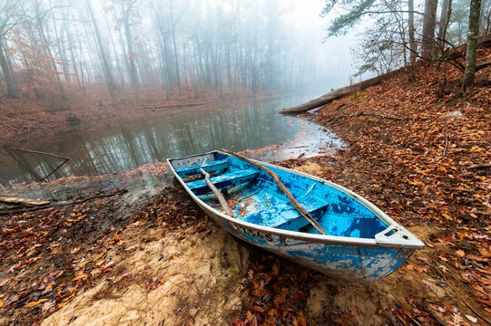 An empty blue rowboat sits on the shore of a small lake on a foggy morning at Boat Rock, a recreational area south of Atlanta, Georgia. 
