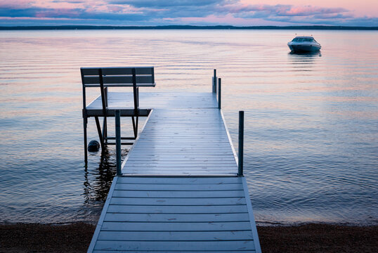 Colorful sunrise and an aluminum dock at Sebago Lake, Maine, with a boat in the distance