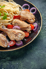 Half shot of raw pastas chickens and vegetables on a plate on green black mix colors background with free space in vertical view
