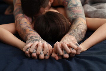 Passionate couple having sex on bed, focus on hands