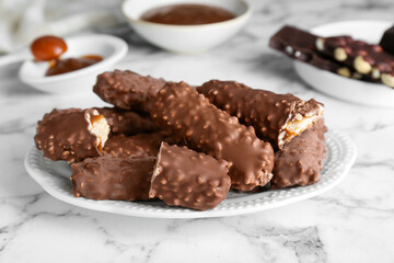 Tasty chocolate bars with caramel on white marble table