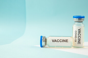 Horizontal view of COVID- VACCINE in closed ampoules on the left side on pastel blue and white background with free space