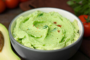 Bowl of delicious guacamole on table, closeup