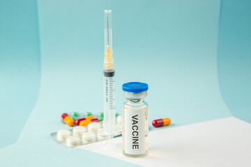 Horizontal view of vaccine for treatment Covid- in medical ampoule packed pills capsules and disposable syringe on white blue background