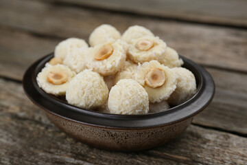Delicious candies with coconut flakes and hazelnut on wooden table, closeup