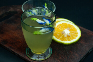 It's a photo of an orange juice extracted from a telecast glass of transparency. Around it are a board, a bowl with eggs and lemon slices