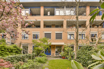 Fototapeta na wymiar an apartment building with trees and bushes in the front yard, looking out onto the street from the garden area