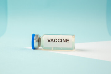 Side view of COVID- VACCINE in a fallen ampoule on pastel blue background with free space