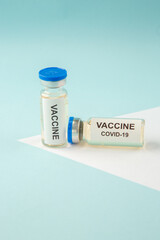 Side view of COVID- VACCINE in closed ampoules on pastel blue background with free space