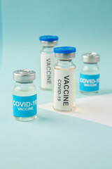 Side view of COVID- vaccine ampoules on pastel blue and white background