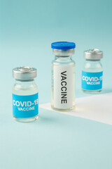 Side view of COVID- vaccine ampoules on pastel blue and white background with free space