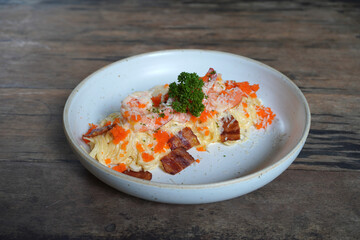 Spaghetti cream sauce with shrimp, crispy bacon and tobiko. Selective focus