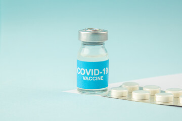 Side view of vaccine in medical ampoule packed pills on pastel blue background