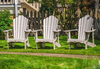 White Adirondack chair setting at the garden. Traditional curveback red wooden beach chair. Red...