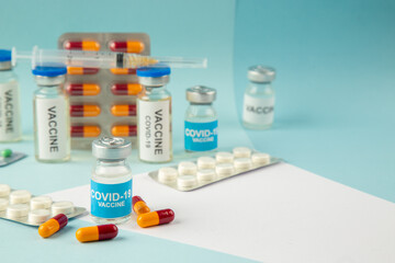 Side view of vaccine in medical ampoules packed pills and capsules for Covid- on blue background