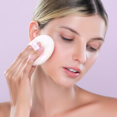 Closeup alluring beautiful female model applying powder puff for facial makeup concept. Portrait of...