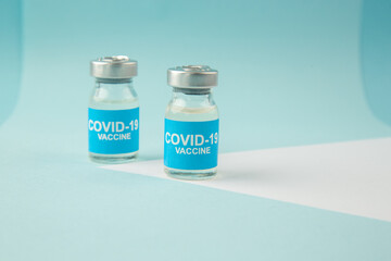 Top view of COVID- vaccine in medical ampoules on white sheet on blue wave background