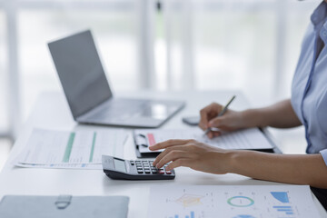 Close up of businesswoman Accounting using calculating income-expenditure and analyzing real estate investment data report Financial and tax systems concept.	