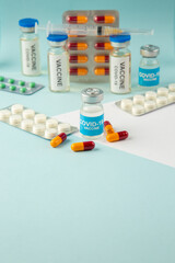 Top view of covid- vaccine in medical ampoules packed pills capsules on blue background