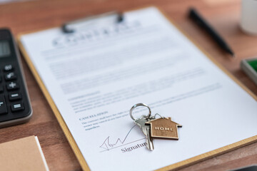 House key on top of house loan or mortgage contract document over table in office as symbolic of...
