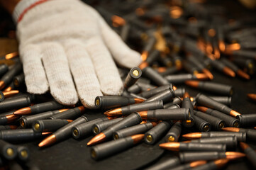 Woman in gloves sorts finished cartridges at plant workplace