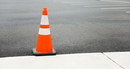 Orange construction cones, symbols of road work and caution, stand on the street under the bright...