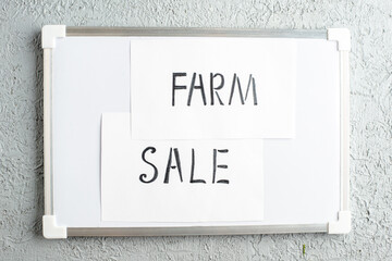 Top view of SALE FARM writings on sheets on white desk on gray sand background