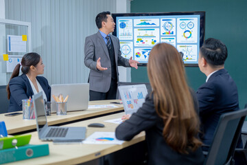Office Conference Room Meeting Presentation: asian Businessman Talks, Uses Wall TV to Show Company Growth with Big Data Analysis, Graphs, Charts, Infographics. Multi-Ethnic e-Commerce Startup 