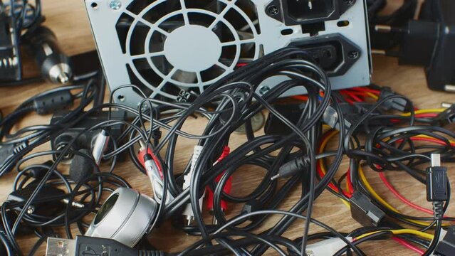 Bunch of old wires, connections, headphones and chargers for electronic devices Old wires, connections, headphones and chargers close-up on wooden table. Concept of obsolescence of electronic devices