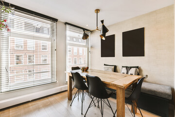 a dining table and chairs in front of a window with shutters on the windowsilling is white brick
