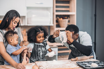 Family members cook homemade pizza dough in funny and playful ways. Mixing ingredients like salt,...