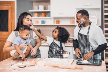 Family members cook homemade pizza dough in funny and playful ways. Mixing ingredients like salt, sugar, milk, yeast, oil then rubbing, massaging, pressing bread flour to make it smoother, stretchier