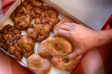 Hands choosing sweet selection of gluten free doughnuts from a box