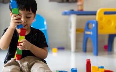 Three-years-old Asian boy builds figures from large plastic parts with interest and excitement.