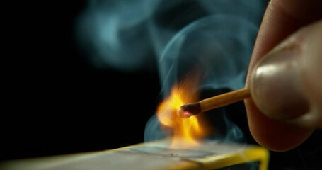 Match smoke, hand and orange flame with strike and ignite in studio with dark background. Flames, fire and heat with matchbox and smoking from burning light and glow with danger and spark holding box