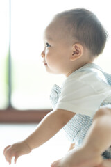 Chubby ginger baby boy in bodysuit, barefoot. He smiling, creeping on floor background with copy space, family fatherhood and parenthood concept, happy little baby girl with father at home