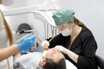 dentist professional filling teeth for man patient sitting in medical chair. High quality photo
