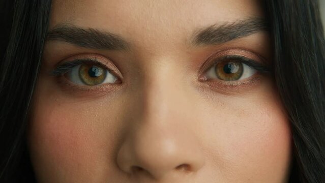Gorgeous girl opening beautiful green, brown, hazelnut eyes. Brazilian young female model with big eyes looking at camera. Slow motion macro extreme close up 4K shot. Close up of latino woman face