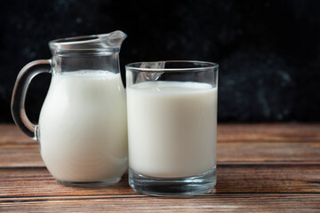 Obraz na płótnie Canvas Fresh milk in a mug and jug on wooden table