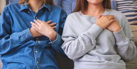 Closeup image of a young couple women with hands on chest
