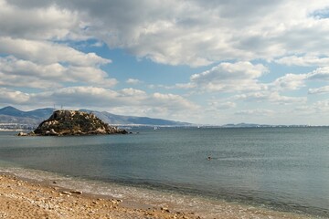 Beautiful photo of calm Votsalakia beach (Riviera Beach) without people with small island in the background, Pireaus