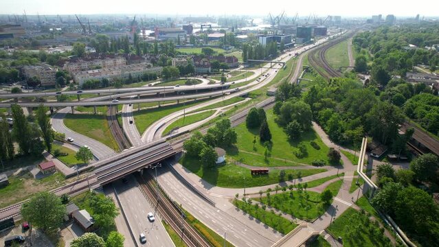 Aerial flyover intersection and road with bridges and traffic in Gdansk during sunny day - Industrial harbor cranes in background
