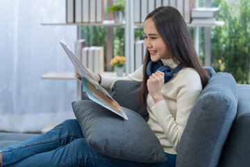 Obraz premium Young woman planning a trip and holding a map in the living room.