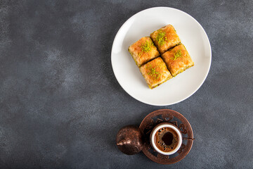 Traditional pistachio baklava with Turkish coffee on black background,top view
