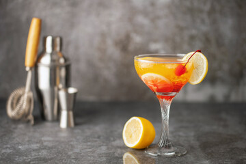 Summer limoncello sunrise cocktail with lemons and maraschino cherry in a glass